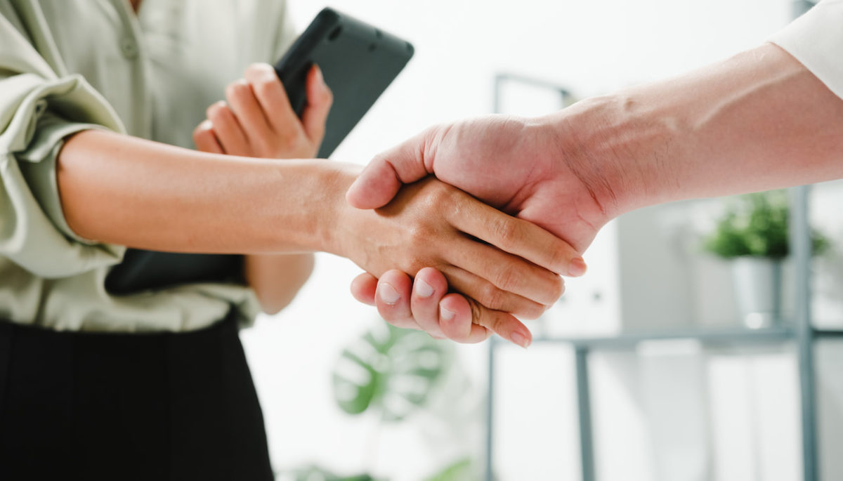 Mujer y hombre estrechan manos como simbolo de negociación exitosa - poder de la negociación de los proveedores