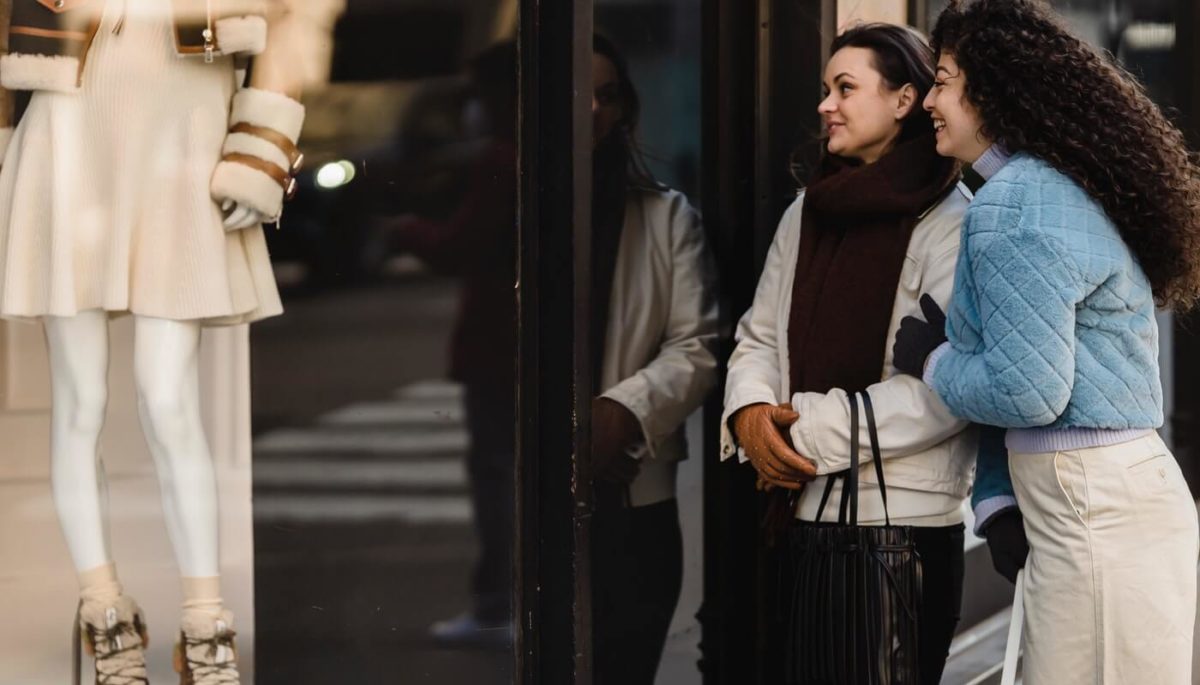 Mulheres olham vitrine, representando o desejo de compra despertado pelo marketing