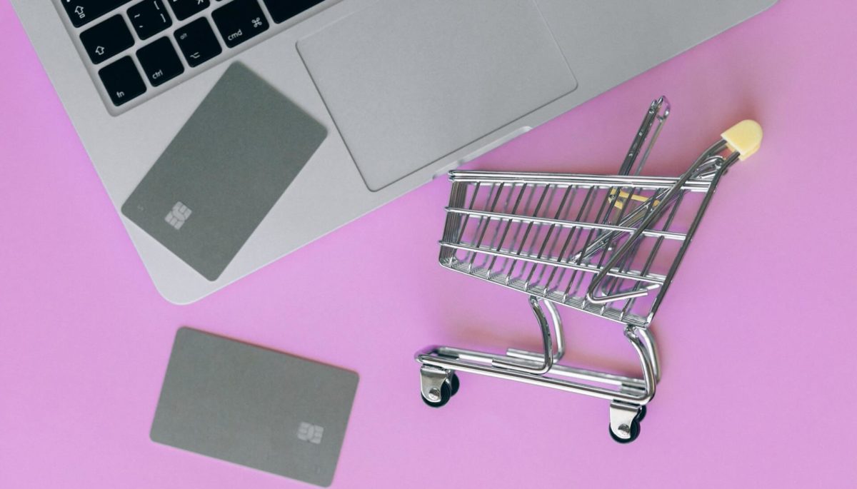 Foto de um carrinho de compras e um computador representando as vendas e-commerce