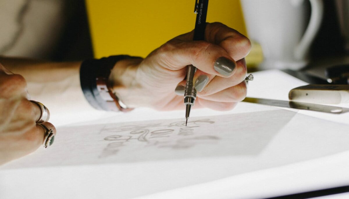Mão de mulher desenhando representa como criar um logo