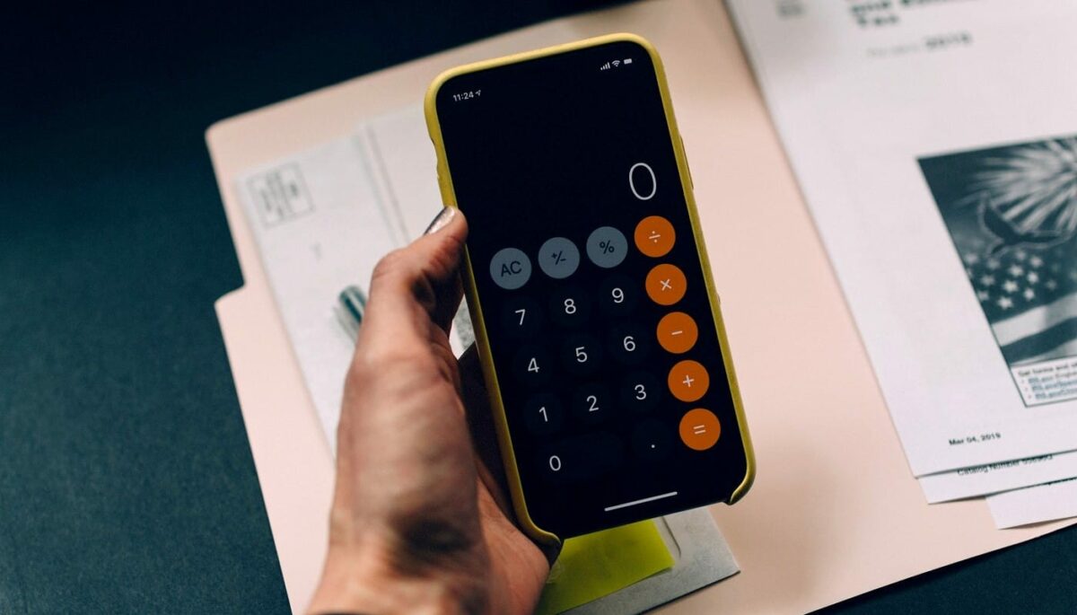 Mão segura smartphone aberto na calculadora, representando o que e contabilidade gerencial