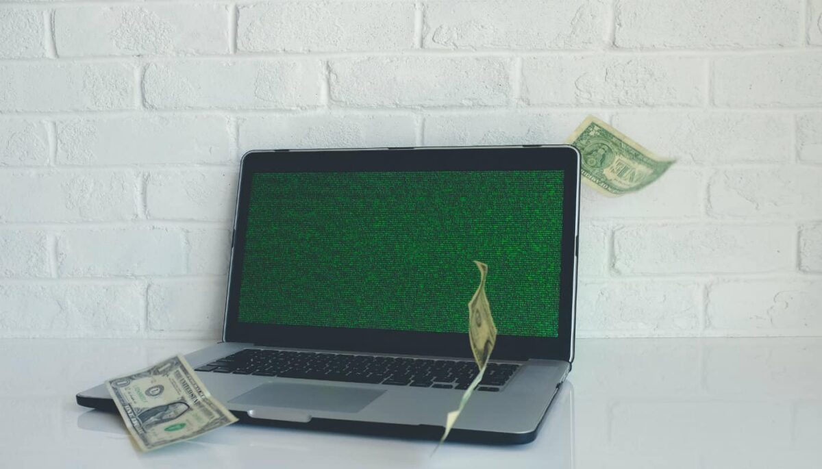 Como encontrar fornecedores da China para vender na internet? Computador com cédulas voando ao seu redor representa os fornecedores internacionais dropshipping