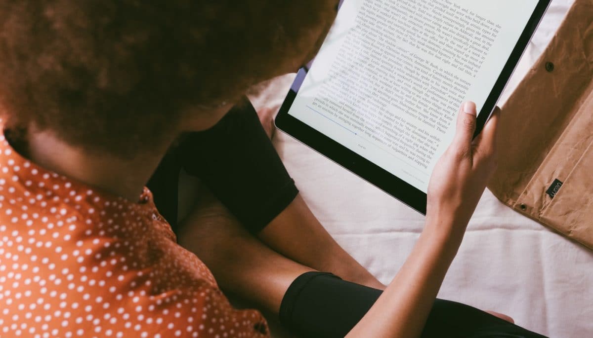 Imagem mostrando uma mulher lendo um e-book por meio de um tablet.