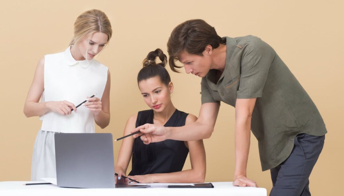 Duas mulheres e um homem olham para tela de computador, como quem pesquisa sobre empréstimo para e-commerce