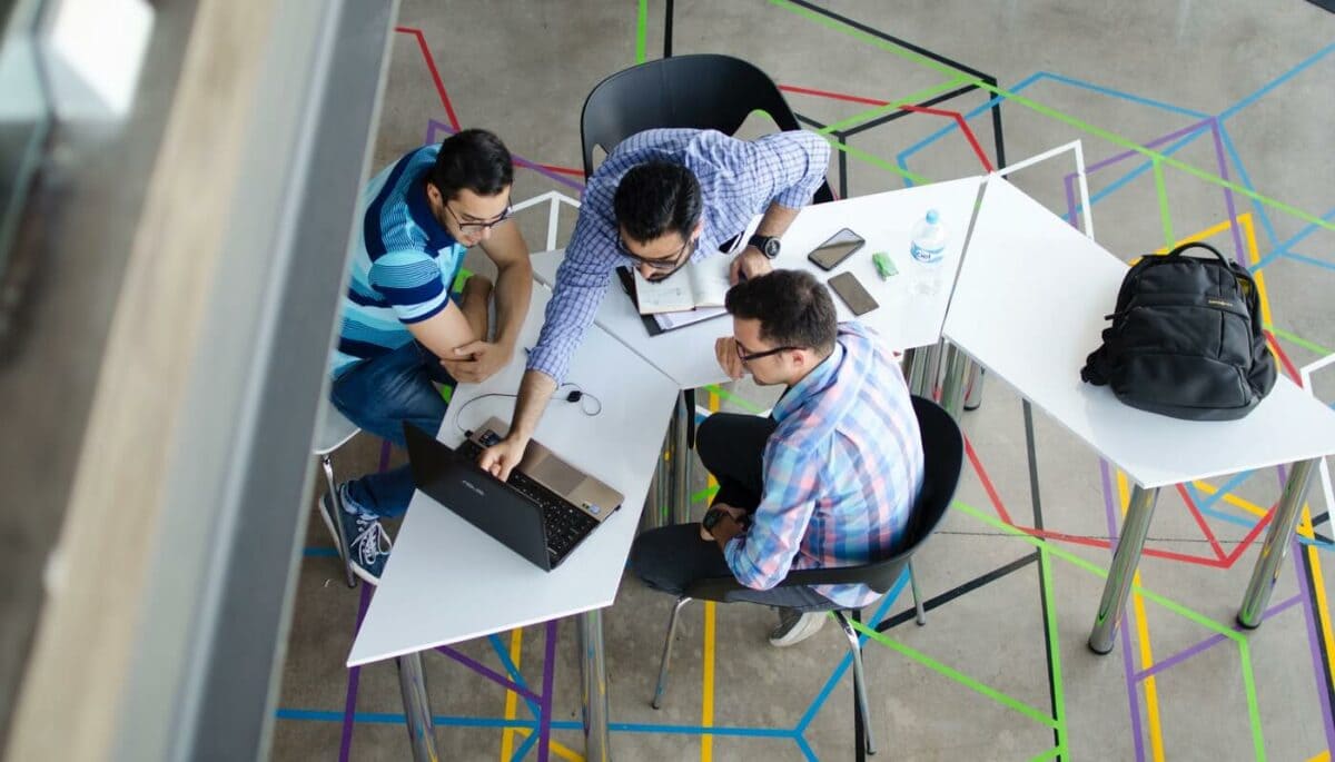 O que é networking, para que serve e como criar uma rede de contatos? Pessoas reunidas ao redor de uma mesa representando networking