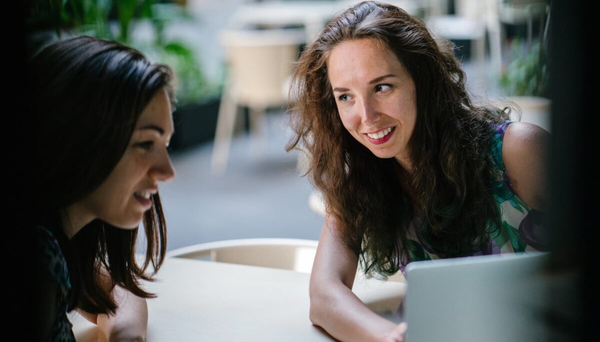 Dos mujeres en una mesa trabajando textos persuasivos en una laptop