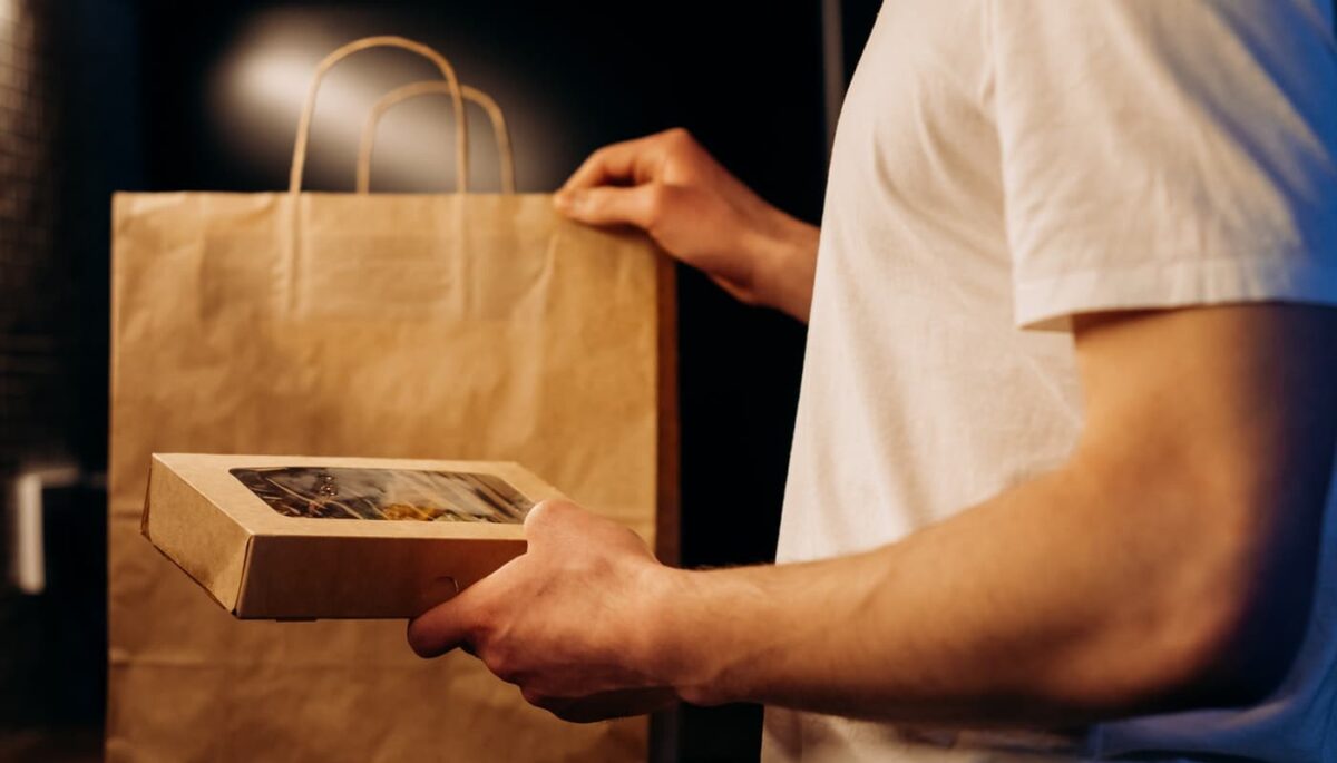 Imagem mostra um homem retirando uma caixa da sacola representando como embalar salgados congelados para vender