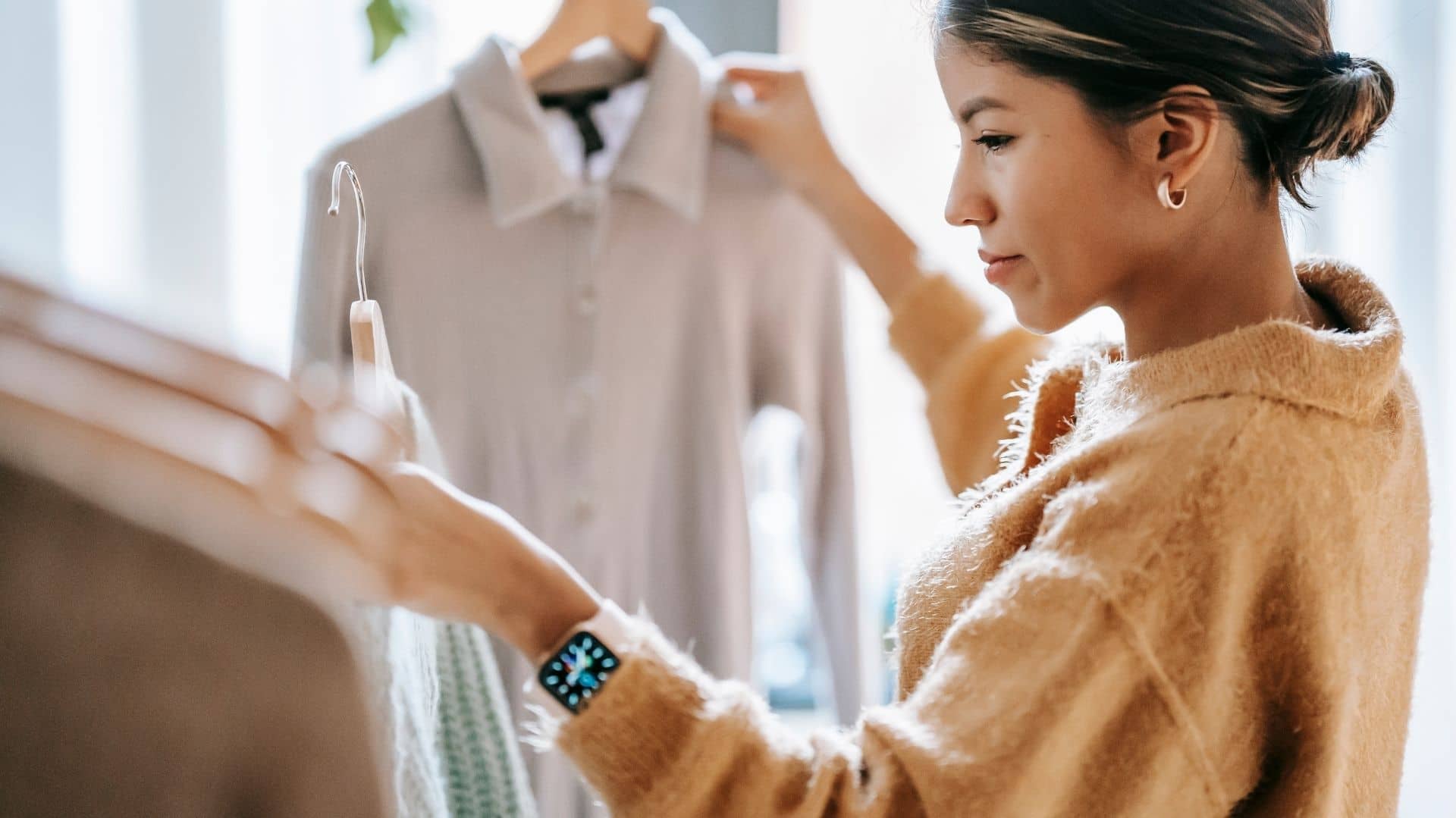 Una mujer mirando ropa y aprendiendo cómo emprender un negocio de ropa