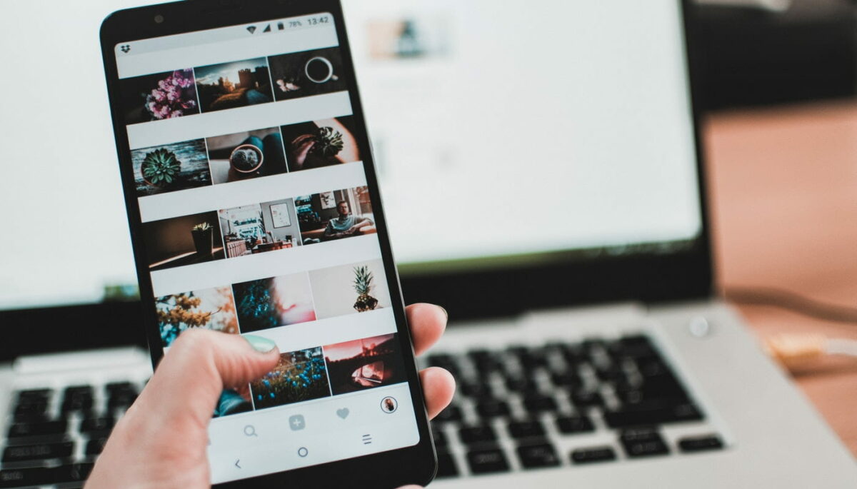 Mão segurando celular aberto em um perfil do Instagram, como se estivesse aprendendo como organizar o feed do Instagram