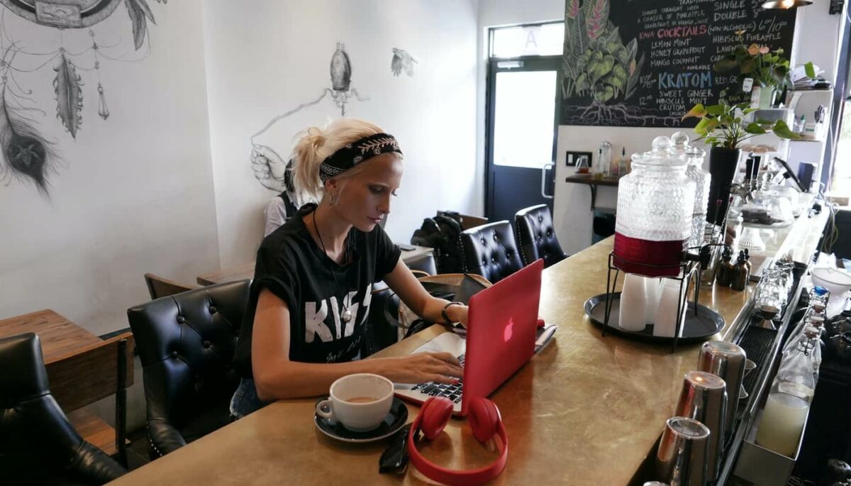 Mulher trabalhando de seu computador em um café, como se estivesse administrando sua loja que é um case Nuvemshop de sucesso