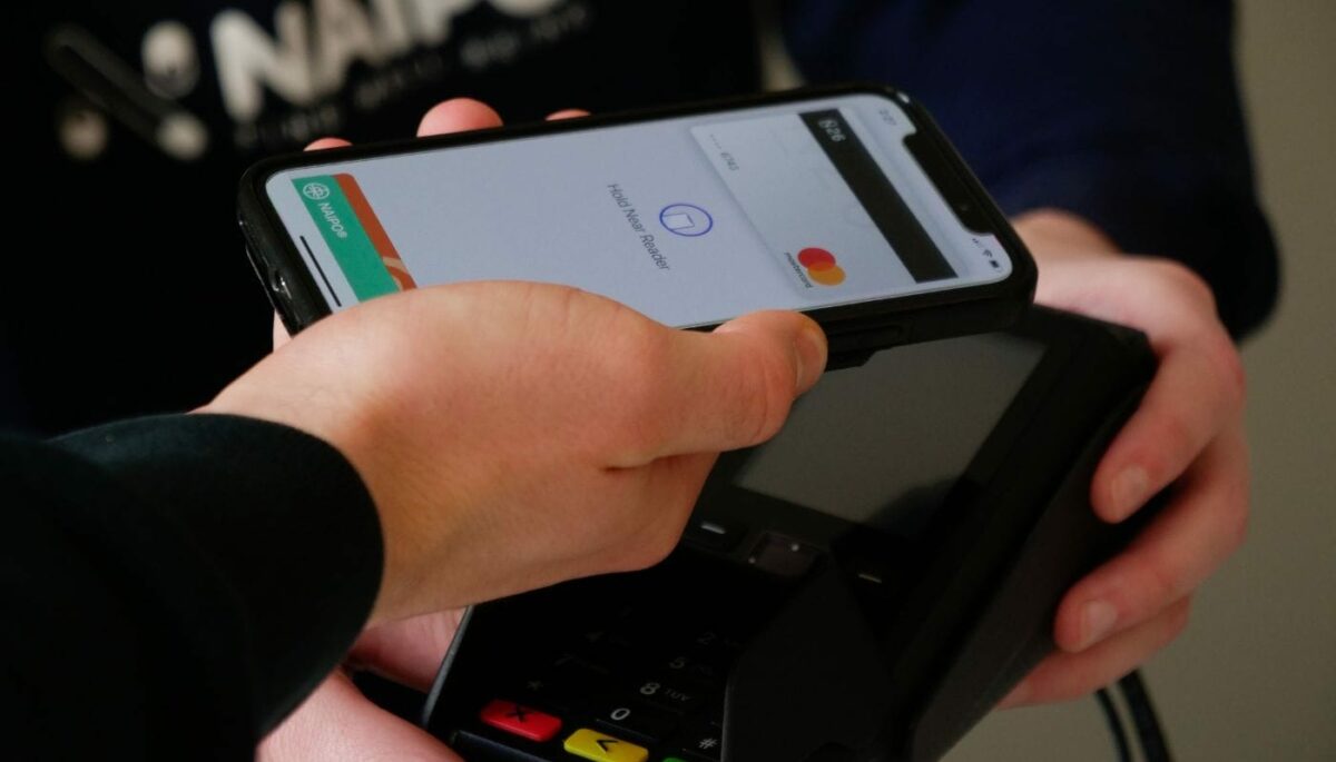 homem faz pagamento por aproximação com o uso de celular, representando como receber dinheiro pelo ame digital
