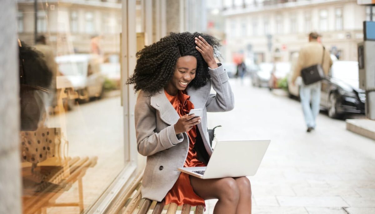 Mulher com cartão na frente de um notebook, como quem está fazendo compras no varejo online