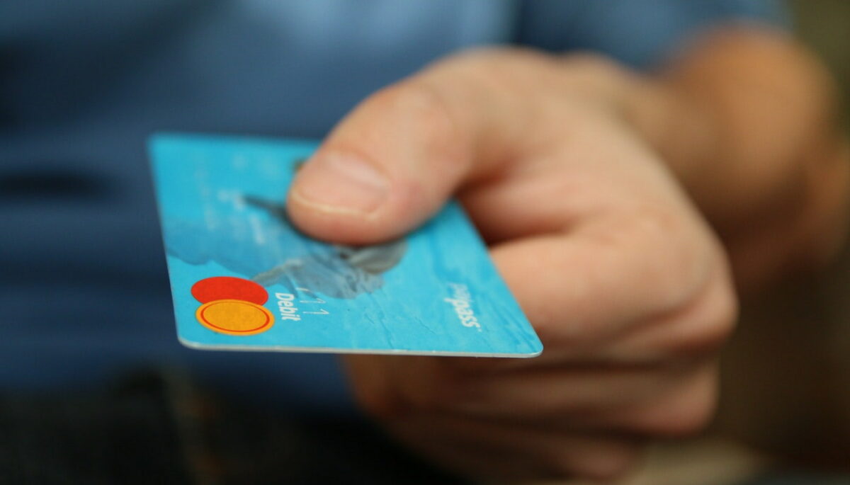Mão segurando cartão de crédito azul, como se estivesse usando o cartão private label de alguma loja