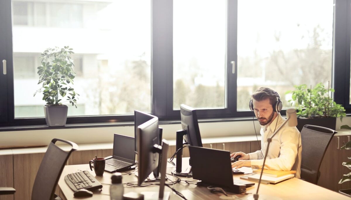 Homem sentado em frente a um computador com fone de ouvido, como se estivesse concentrado realizando alguma tarefa da força de vendas