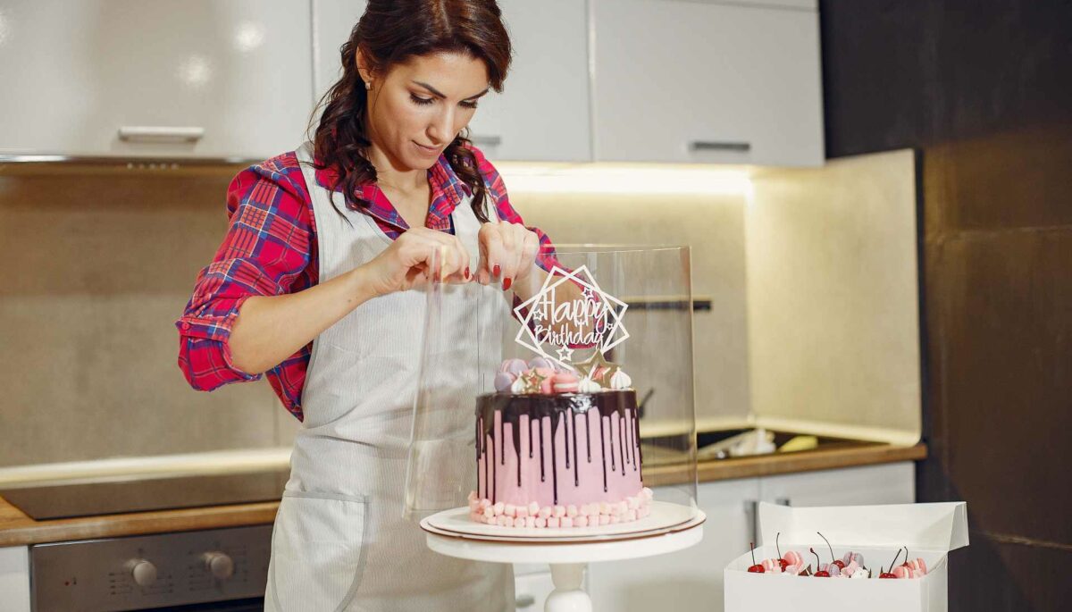 mujer decora un pastel para su negocio de postres