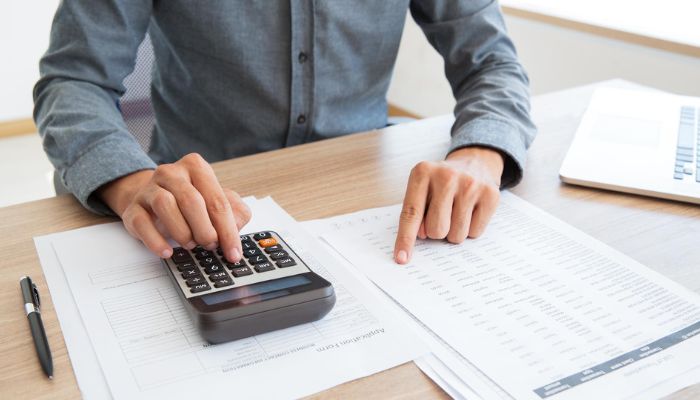 Hombre en un escritorio estableciendo el precio unitario de un producto con su calculadora.
