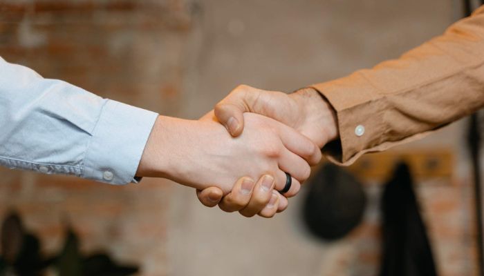 Dos personas estrechan sus manos en señal de un cierre de ventas exitoso.