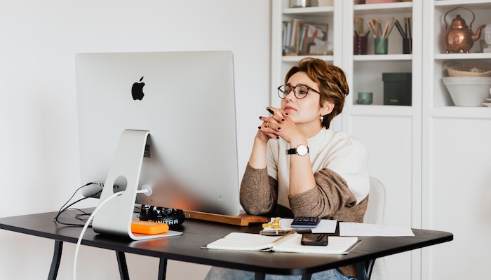 Mujer sentada frente a la computadora, analizando si avanza con un negocio de venta a consignación.