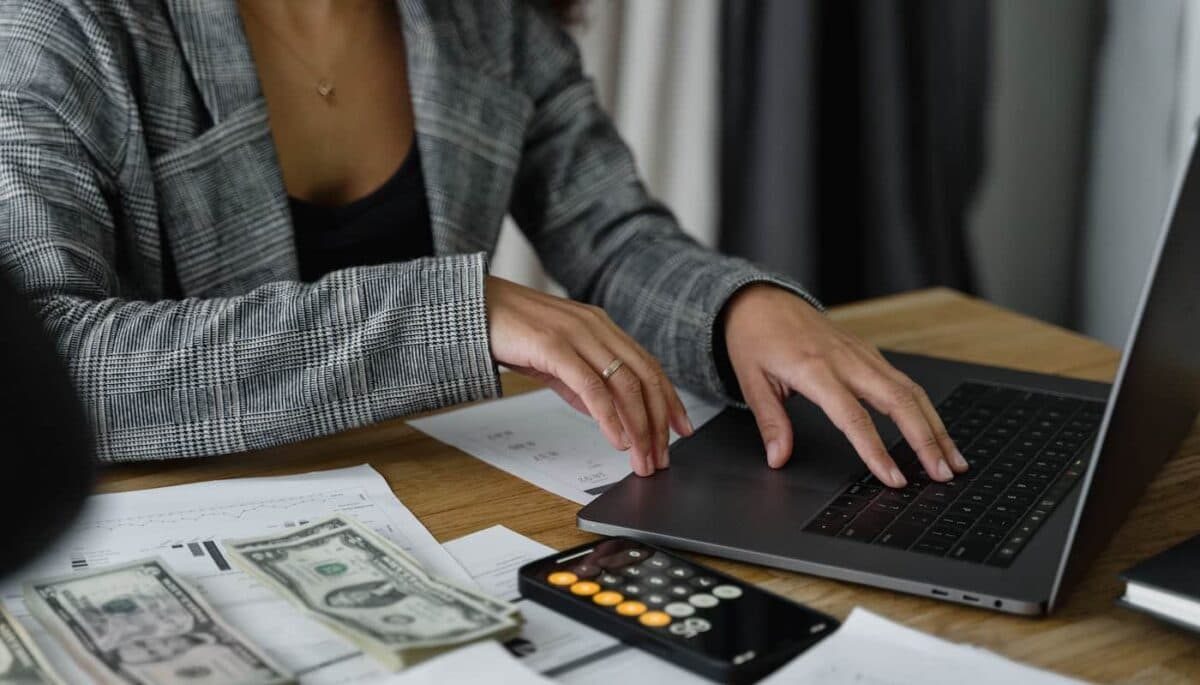 Imagem de uma mulher usando a calculadora e o computador, representando o que é lucratividade