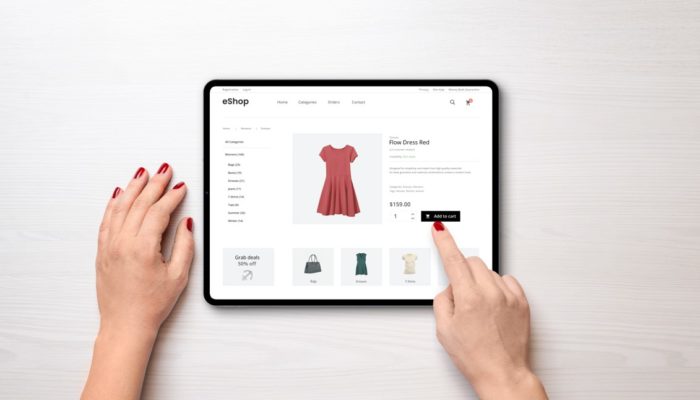 fotografia de las manos de una mujer utilizando una tableta en la que se muestra una página web de un producto de ropa