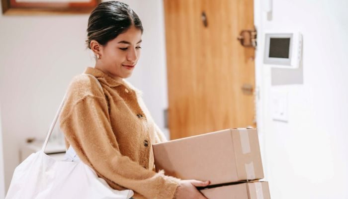 Mujer joven con cajas realiza un pago contra entrega.