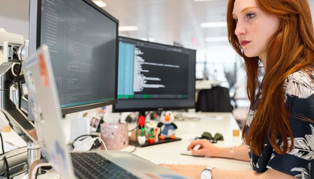 Na imagem, há uma mulher mexendo em um computador, representando como fazer reajuste de preço.