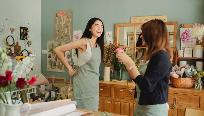 Dos mujeres ríen y trabajan en una florería registrada como mipyme.