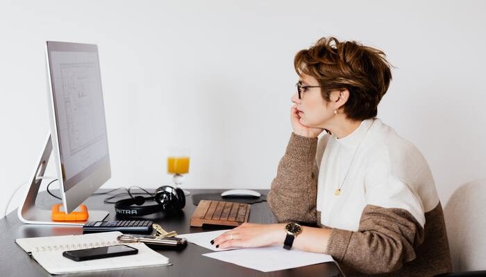 Una mujer investiga en su computadora cómo crear una página en construcción para su tienda online.