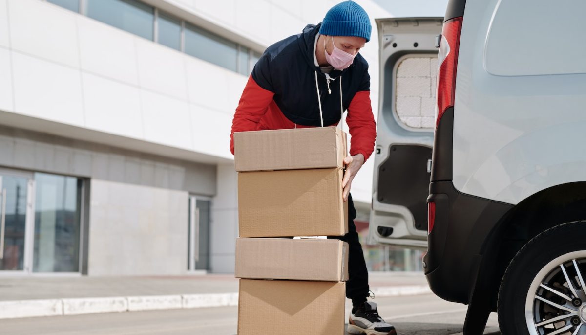 Na imagem, vemos um homem carregando algumas caixas para fazer uma entrega
