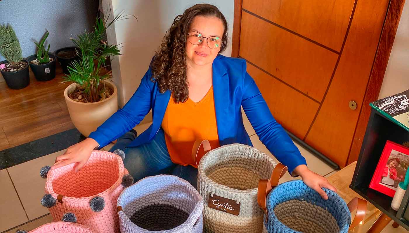 Empreendedora do Ateliê Pontos e Fios posa com suas cestas de crochê artesanais.