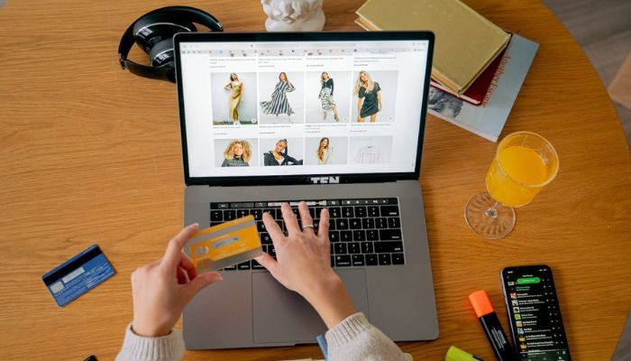 El escritorio de una mujer que sostiene su tarjeta de crédito en la página de checkout de una tienda online de ropa.