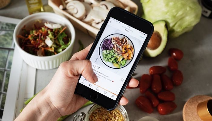 Un emprendedor toma fotos de su negocio de comida para publicar en el Instagram comercial de su marca.