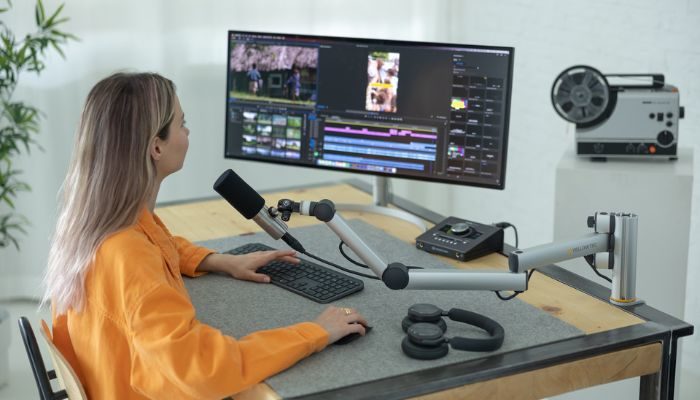 Una mujer utilizando su plataforma digital para edición de audio y video en la computadora.