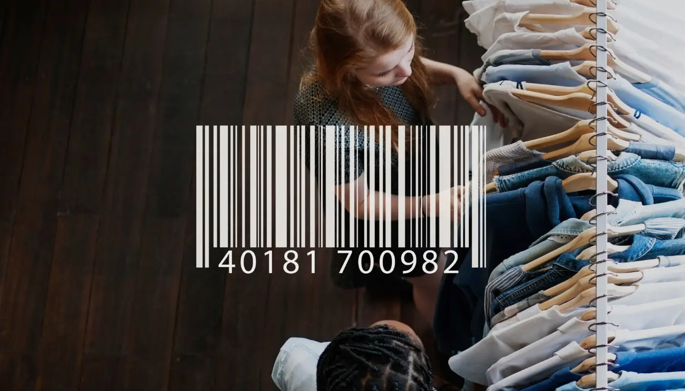 Ao fundo, duas mulheres são vistas de cima mexendo em uma arara de roupas. Sobre a foto, tem a imagem de um código de barras representando o código universal do mercado livre.