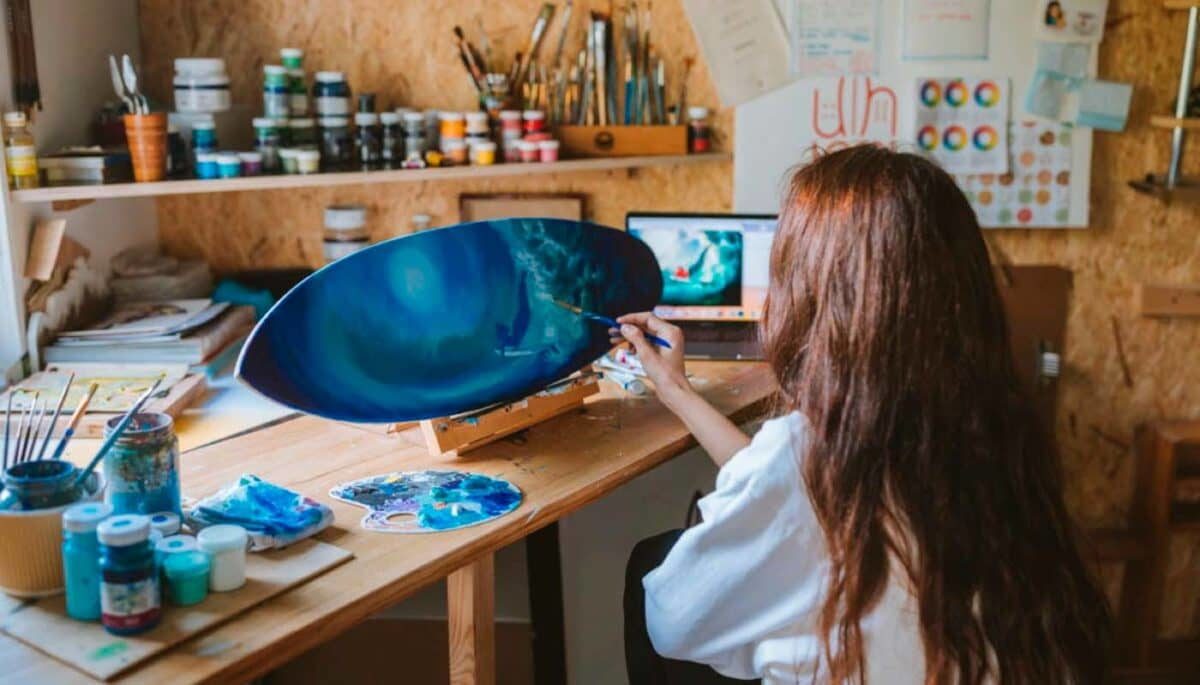 Imagem mostrando uma mulher pintando uma prancha de surf para vender no Elo7.