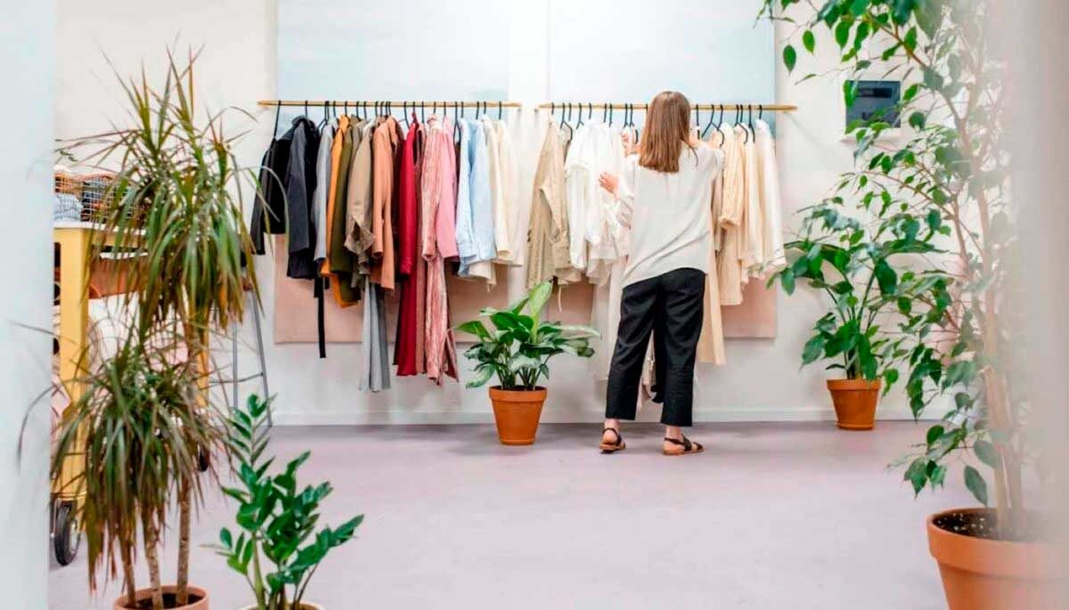 Mulher manuseando roupas em uma arara, como se fosse a dona de uma loja querendo aprender como vender roupas no Instagram