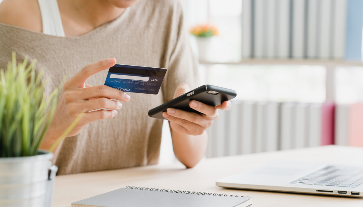 Mujer haciendo un pago en cuotas con su tarjeta de crédito desde su celular.