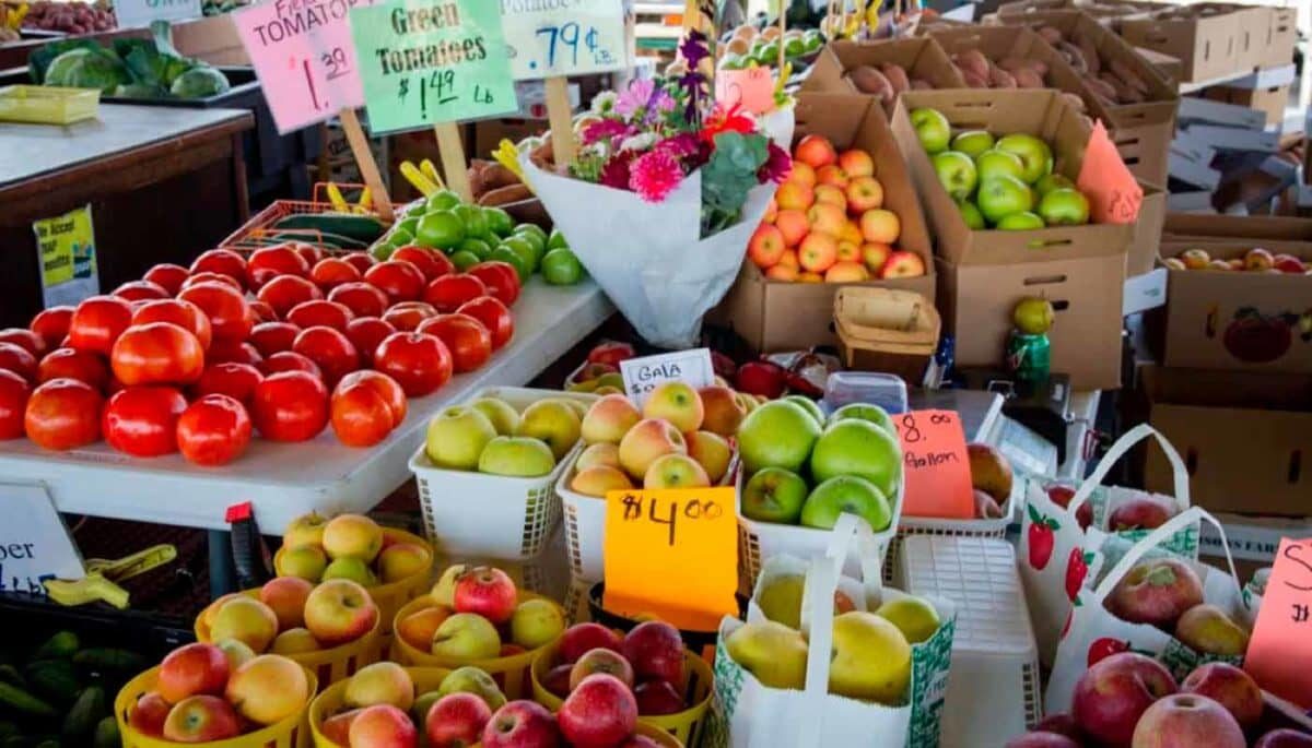 Frutas dispostas para venda no mercado com placas de preços, como se fosse de alguém tentando aplicar a psicologia dos preços.