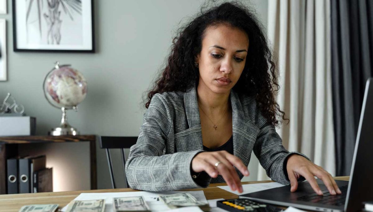 Empreendedora negra descobre como funciona boleto bancário parcelado em seu notebook.