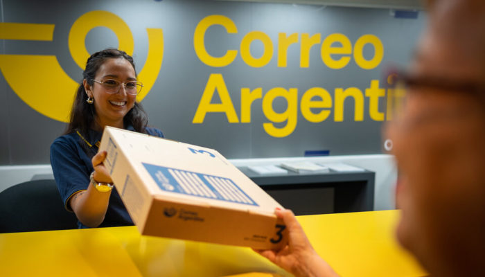 Mujer recibiendo un paquete para envío internacional en Correo Argentino.