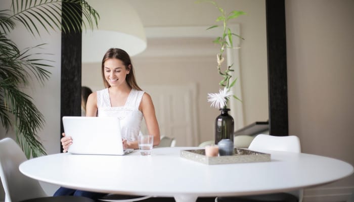 Mujer buscando ideas de negocios online desde casa en su computadora.
