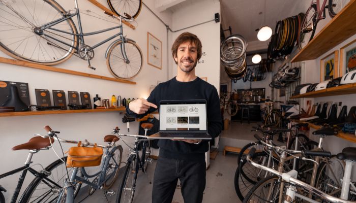 Emprendedor mostrando su Tiendanube gratis en la notebook en su depósito de bicicletas.