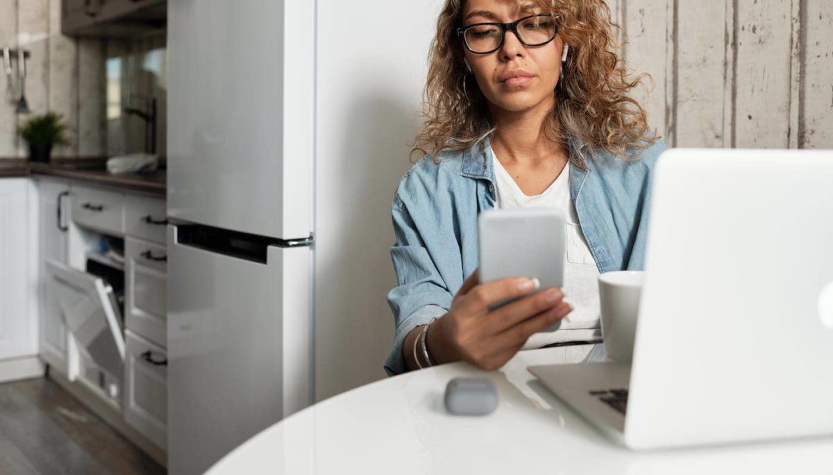Mulher com smartphone na mão representando trabalho online pelo celular.