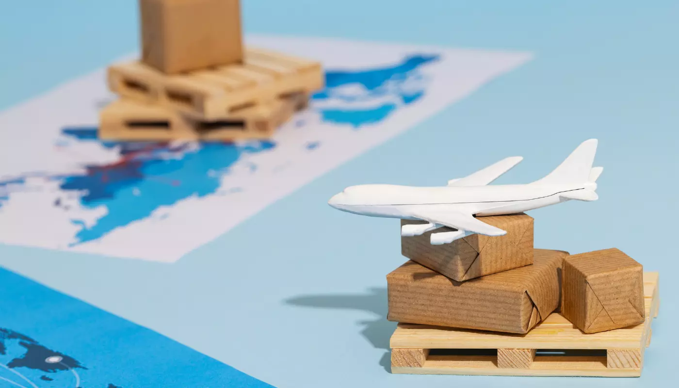 Imagem mostra um mapa e uma miniatura de avião sobre caixas de encomenda. É uma representação do processo de como importar pelo Alibaba.