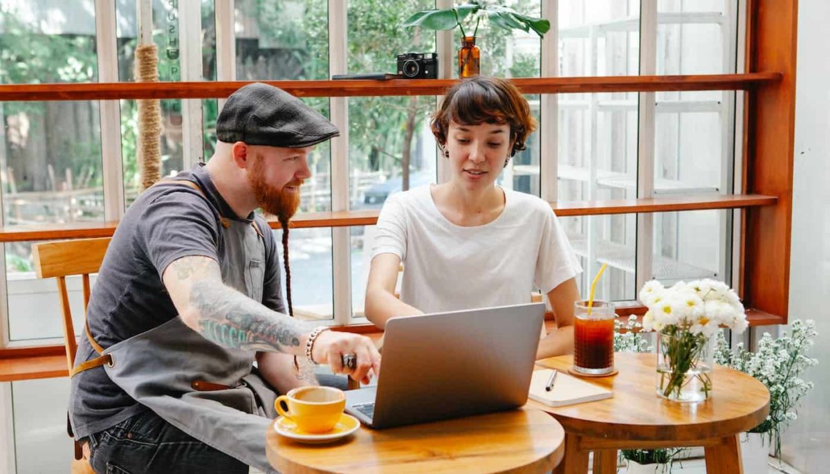 Duas pessoas olhando para o computador e conversando, representando o que é Perfit email marketing.