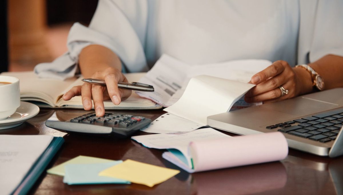 imagem de mulher fazendo contas em uma mesa de escritório, o que pode representar a amortização de uma dívida