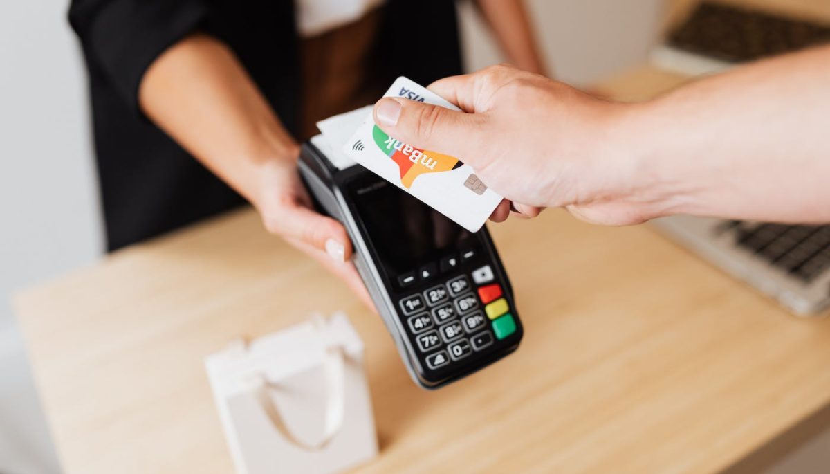 pessoa passa cartão de crédito em maquininha de cartão para representar texto de domicílio bancário