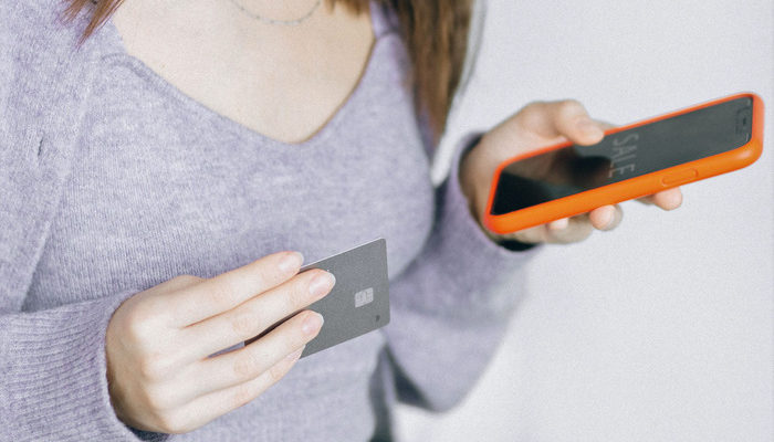 Mujer haciendo un metodo de pago electronico con celular en mano