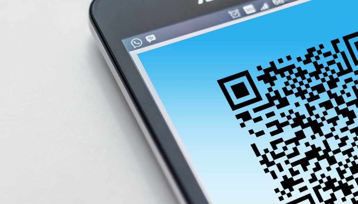 Imagem de celular com QR code na tela, representando texto sobre Pix Cobrança