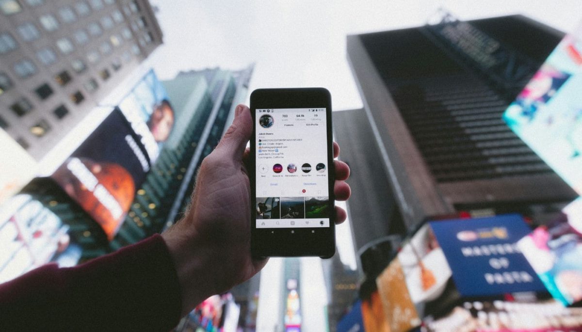 imagem de uma mão segurando um celular com o celular e o app do Instagram aberto.